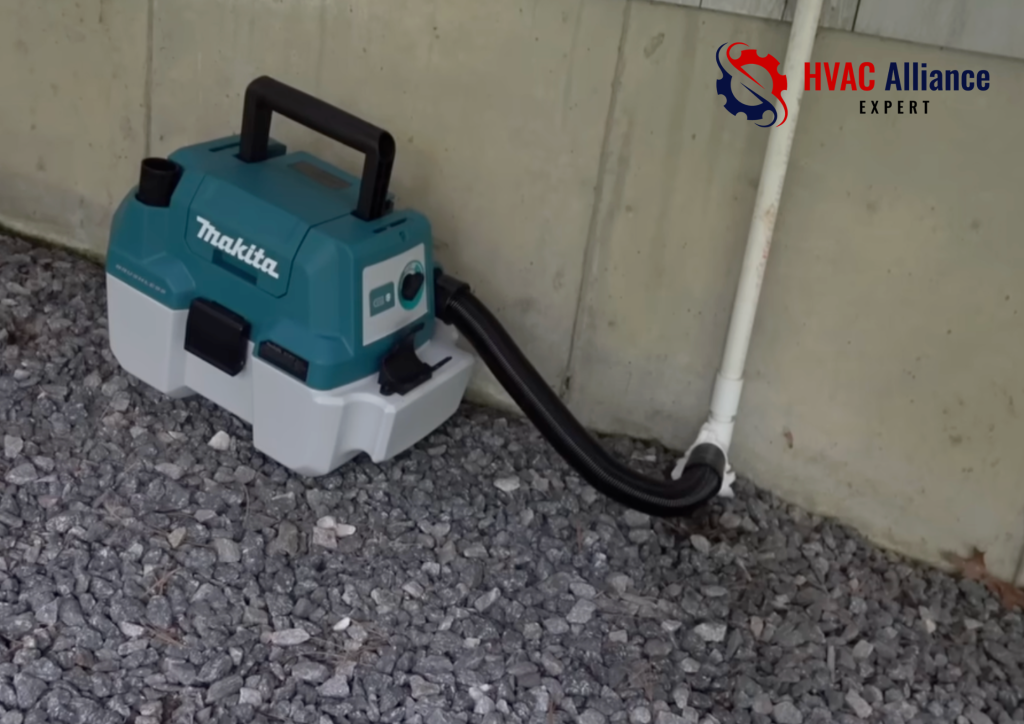 Cordless wet dry shop vacuum hose attached to white PVC AC drain pipe on exterior wall to clear condensate line blockage