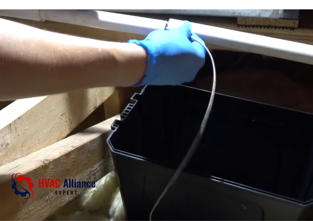 Bucket placed under AC drain line in attic to catch water during condensate drain cleaning process
