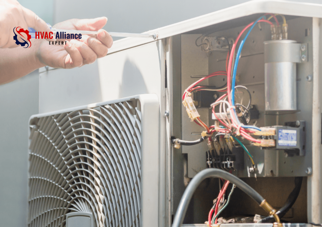 An HVAC technician using a screwdriver to remove the side panel of an outdoor air conditioning condenser unit, revealing the internal electrical components, capacitor, and wiring.