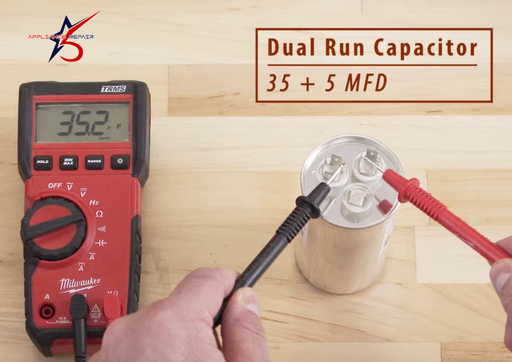 A technician using a digital multimeter to test the capacitance of an AC start capacitor. The multimeter display shows a reading of 1.22 microfarads (uF).